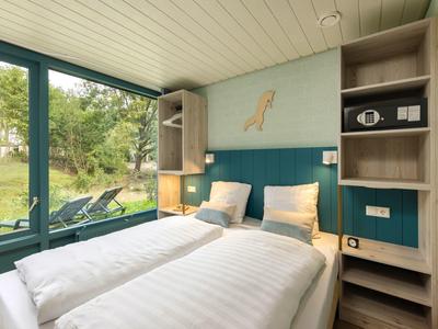Cozy hotel room with two single beds, large window, and view of greenery.