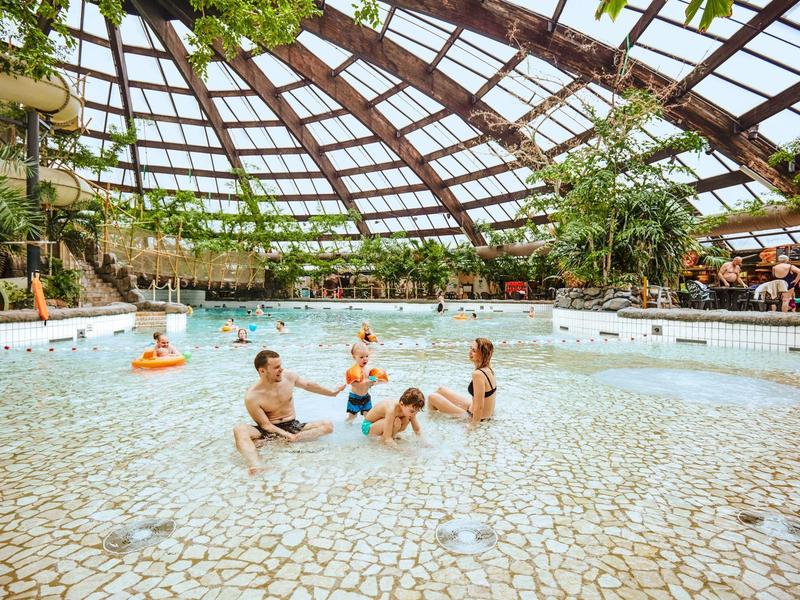 Indoor pool with dome roof, people swimming and relaxing