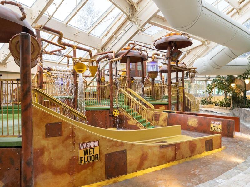 Indoor tropical water park area with wide slides and climbing structures.
