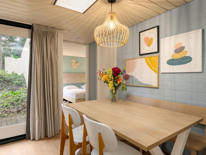 Bright dining area with wooden table, colorful flower bouquet, and modern wall decor