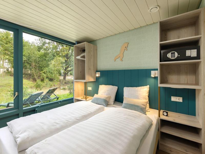 Cozy hotel room with two single beds, large window, and view of greenery.