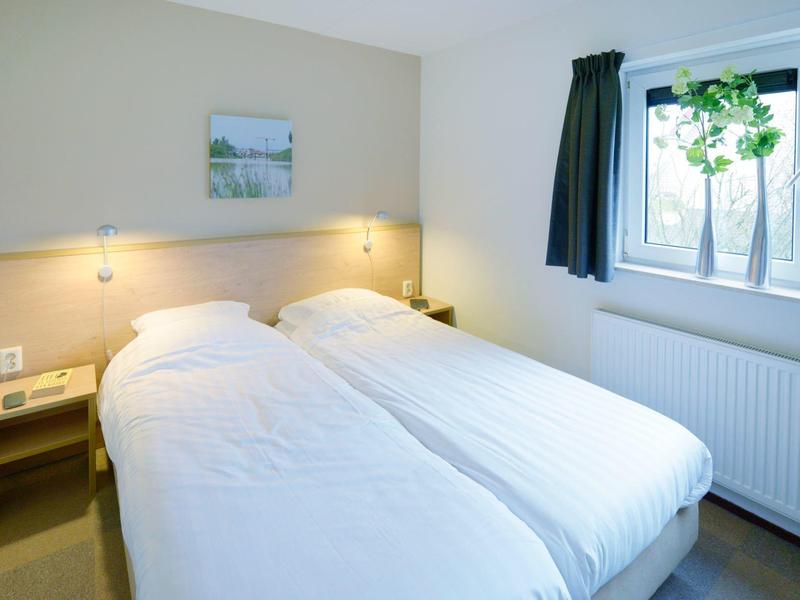 Gezellige hotelkamer met twee eenpersoonsbedden, nachtkastje en raam met gordijn.