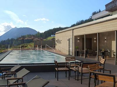 Dachterrasse mit kleinem Pool, Tischen und Stühlen, Bergblick im Hintergrund.