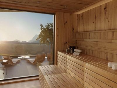 Drewniana sauna z widokiem na taras i góry o zachodzie słońca.