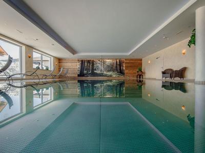 Basen kryty z widokiem na las i przytulne miejsca do siedzenia w pokoju hotelowym.