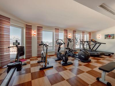 Moderner Fitnessraum mit verschiedenen Trainingsgeräten und großen Fenstern mit Blick auf die Stadt.