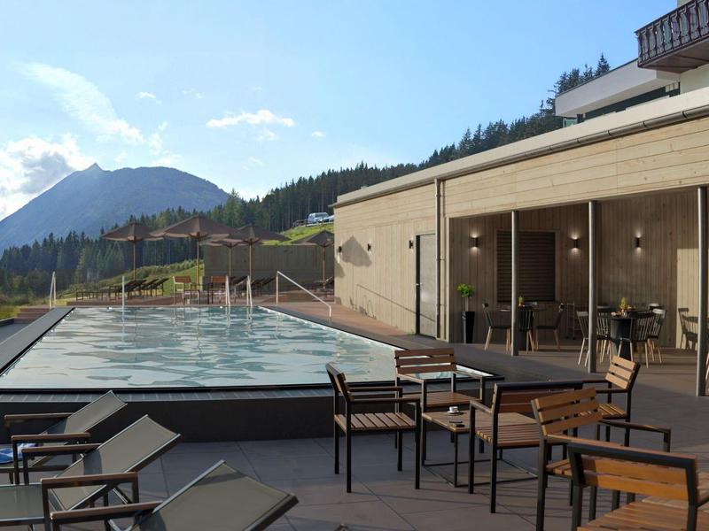 Taras na dachu z basenem i miejscem do siedzenia otoczony górami pod czystym niebem.