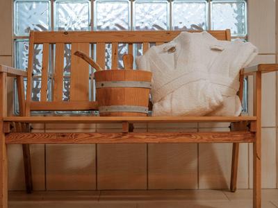 Drewniana ławka z akcesoriami do sauny, oświetlona przez okno z bloczków szklanych.