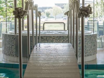 Pomost z poręczami prowadzący do jacuzzi w jasnej strefie wellness.