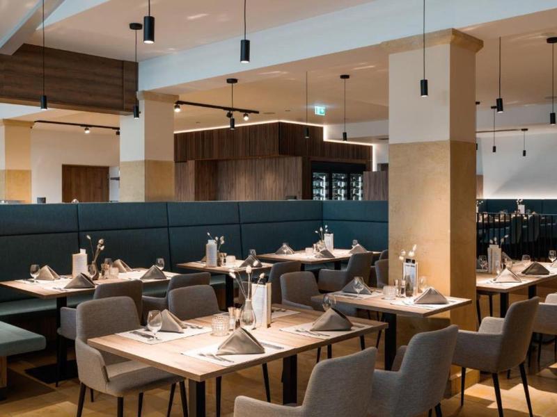 Nowoczesna przestrzeń restauracyjna hotelu z nakrytymi stołami i wygodnymi krzesłami.