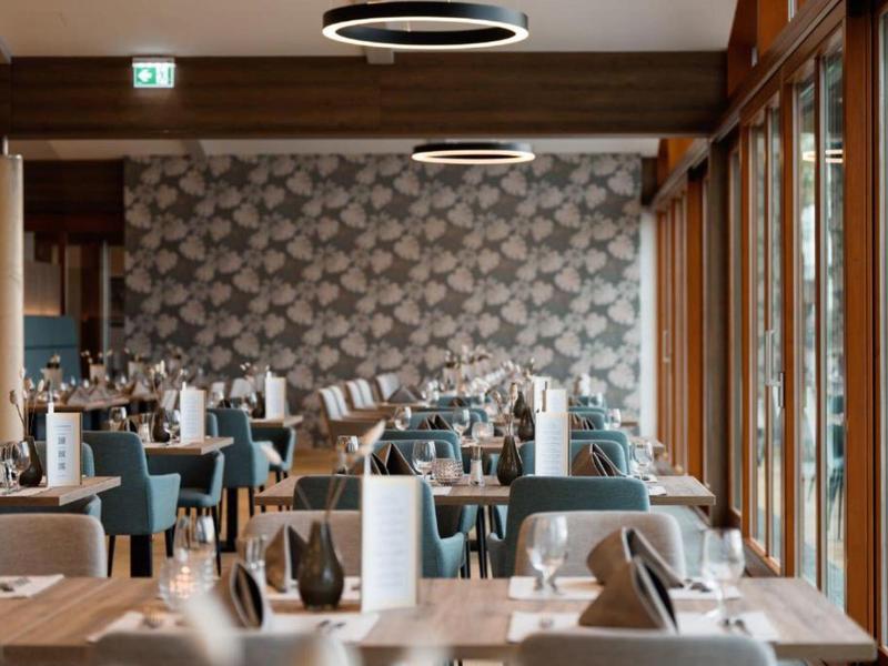 Nowocześnie urządzona restauracja hotelowa z drewnianymi podłogami i dużymi oknami.