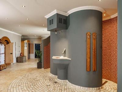 Couloir d'hôtel moderne avec murs courbes, lavabo et accents en bois élégants.