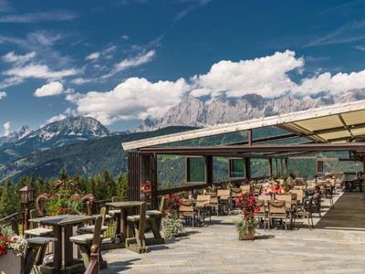 Terrasse d'un restaurant de montagne avec tables, chaises et vue sur des montagnes enneigées.