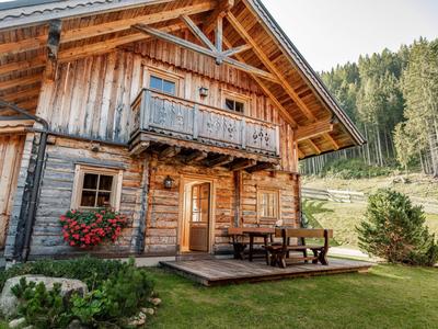 Chalet en bois confortable avec terrasse dans un paysage vert et boisé.