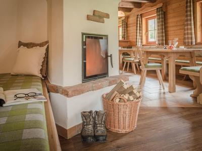 Salle confortable avec poêle à bois, panier de bois, bottes et table à manger dans une cabine en bois.