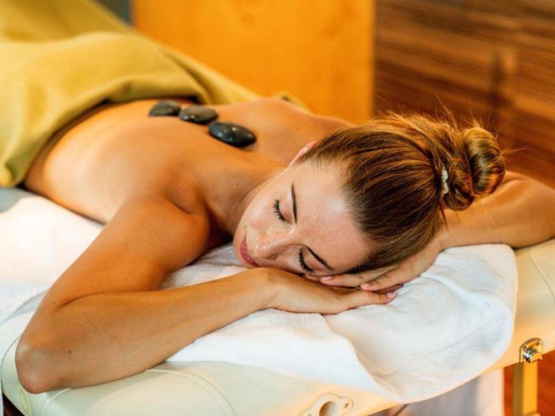 Femme se détendant avec des pierres chaudes sur le dos dans une salle de spa.