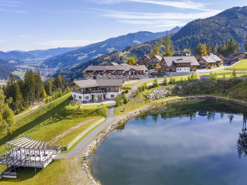 Paysage de montagne idyllique avec lac, sentier et hôtel chalet au soleil.