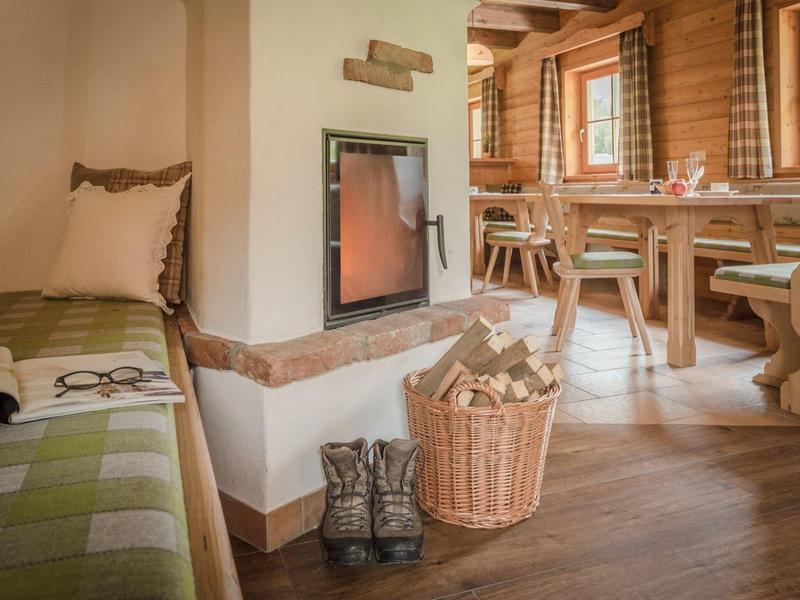 Salle confortable avec poêle à bois, panier de bois, bottes et table à manger dans une cabine en bois.