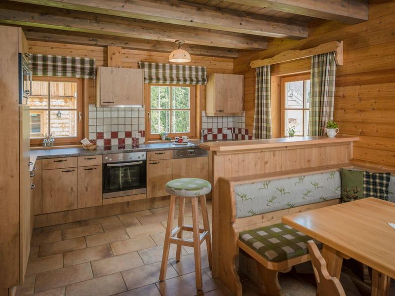 Coin cuisine et salle à manger confortable dans un chalet en rondins rustique avec fenêtres et sol carrelé.