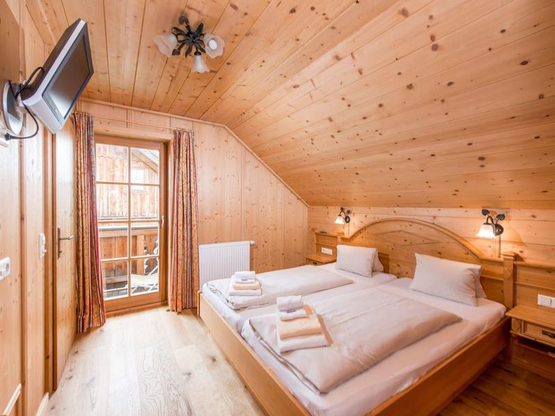 Chambre en bois confortable avec lit double et balcon de style campagne.