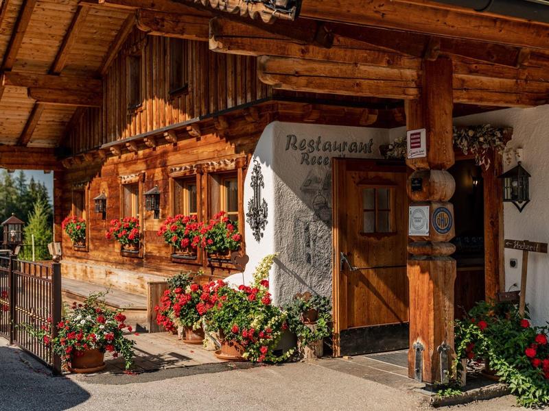 Restaurant de style rustique avec revêtement en bois et fleurs à la porte d'entrée.