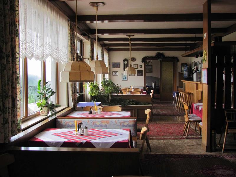 Przytulna restauracja z drewnianymi meblami, kratowanymi obrusami i dużymi oknami z zasłonami.