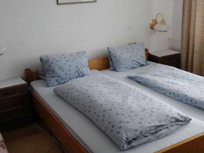 Pokój z dwoma pojedynczymi łóżkami, niebieskimi poduszkami i kołdrami, stolikami nocnymi i lampami.