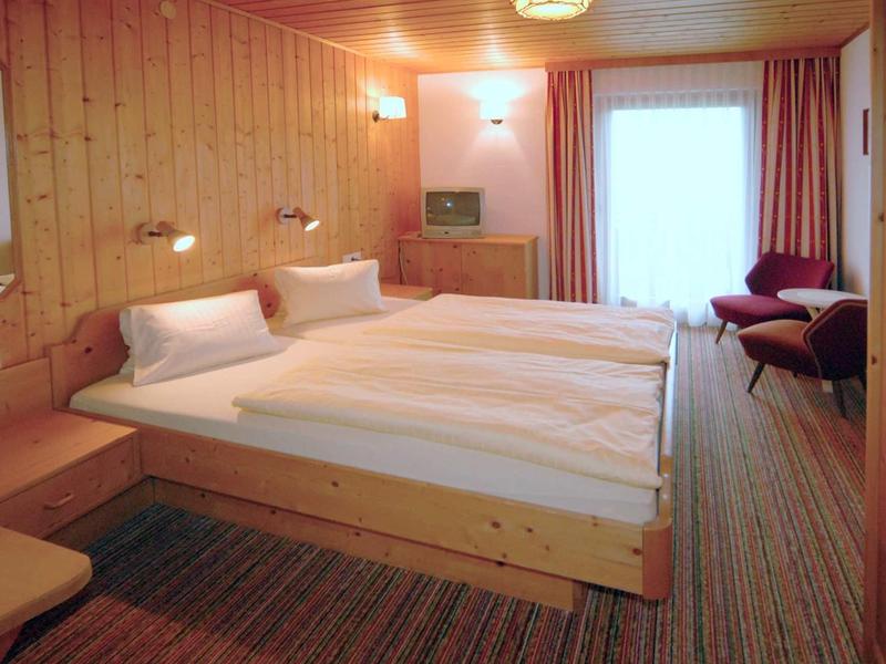 Gezellige slaapkamer met houten wanden, twee bedden en een raam met gordijnen.