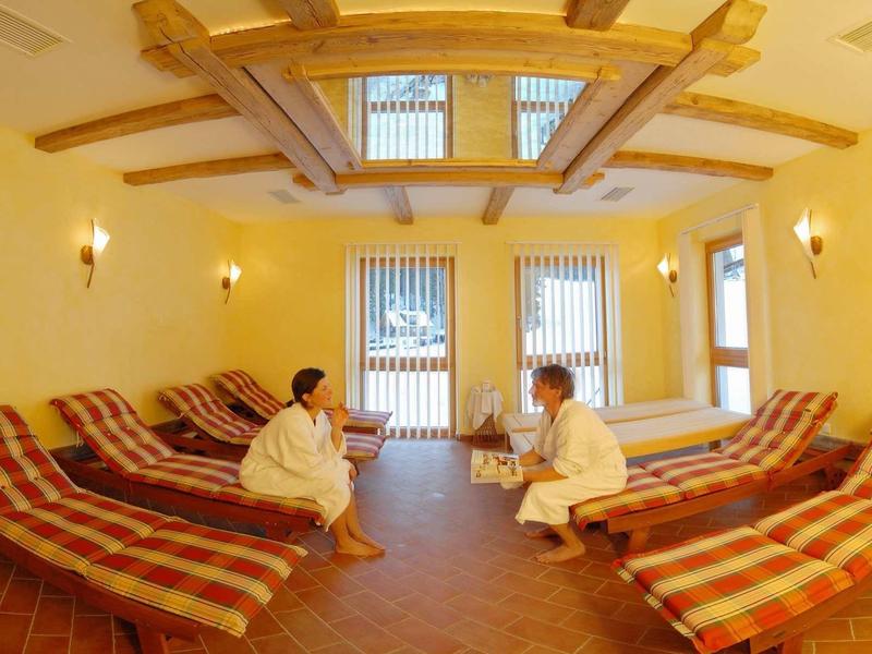 Gezellige ontspanningsruimte met ligstoelen en warm licht, twee mensen ontspannen in badjassen.