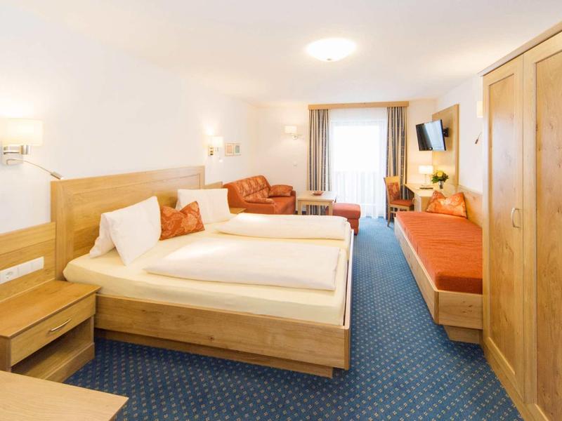 Gezellige hotelkamer met tweepersoonsbed, bank, zithoek en tapijt.