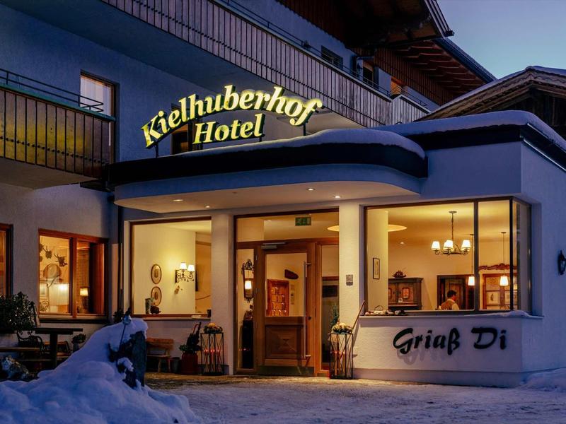 Ingang van een hotel met verlicht bord en sneeuw op de voorgrond bij schemering