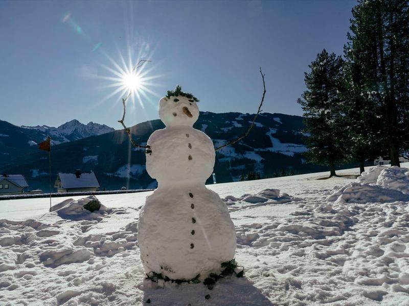 Sneeuwpop met felle zon op de achtergrond op besneeuwd bergterrein.