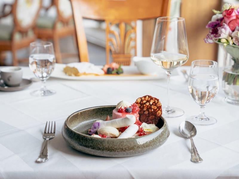 Elegantní prostření stolu s dezertem, sklenicemi a květinami v restauraci.