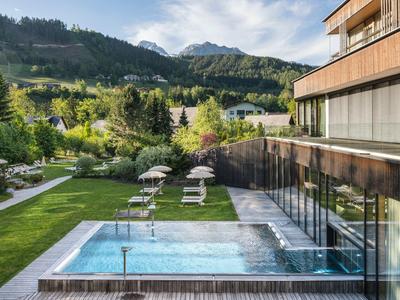 Piscine extérieure moderne avec chaises longues et vue sur la montagne à côté d'un bâtiment hôtelier.