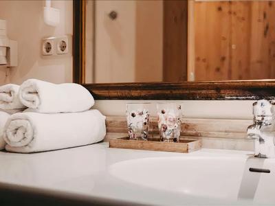 Weiße Handtücher auf einem Badezimmerwaschbecken mit Seifenspender und Spiegel im Hintergrund.