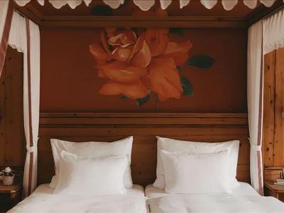 Rustikales Hotelzimmer mit Holzbett und großer Rosendekoration an der Wand