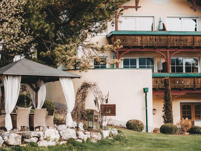 Relaxed outdoor area with a gazebo and chairs in front of a traditional hotel building.