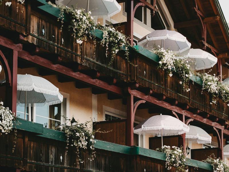Multi-story building with balconies, white umbrellas, and flower arrangements.