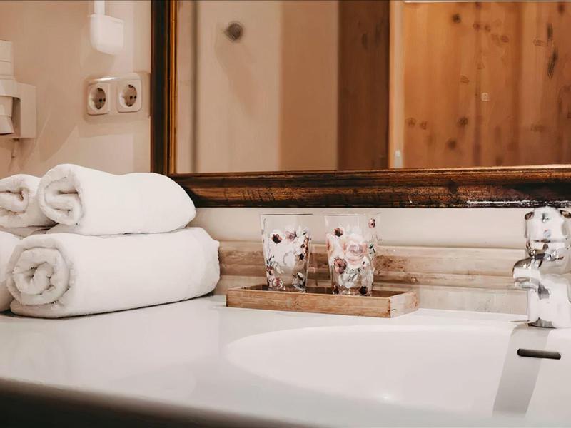 Clean white towels and toiletries beside a sink in a bathroom.