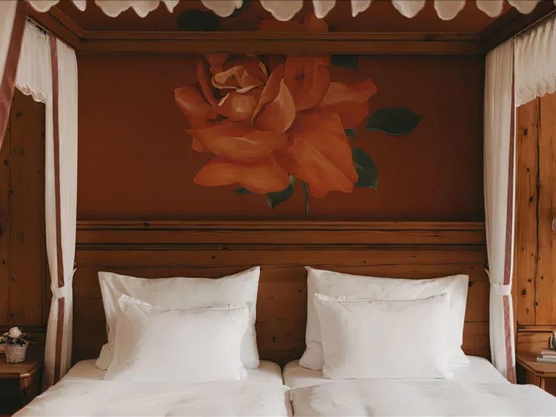 Cozy wooden bed with white pillows and rose painting on the wall in hotel room.