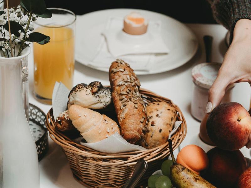 Breakfast with fresh bread, juice, and fruit in a basket on a table.