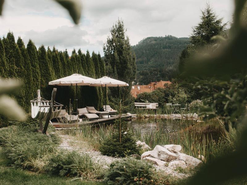 Relaxing outdoor area with sun umbrellas, lounge chairs, and views of trees and mountains.
