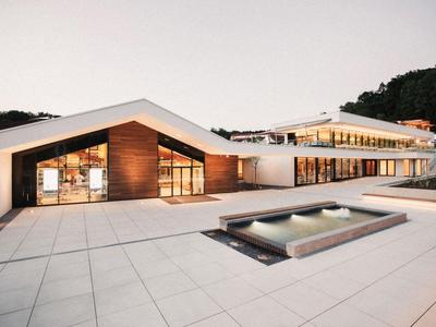 Modernes Hotel mit weißer Fassade, großen Fenstern und Pool im Außenbereich.