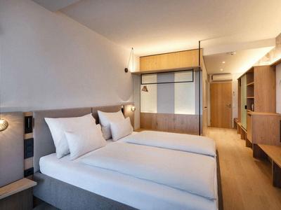 Habitación de hotel moderna con dos camas, muebles de madera y luz cálida.