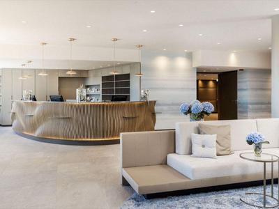 Modernes Hotel-Lobby mit rundem Empfangstresen und bequemen Sitzbereichen in neutralen Farben.