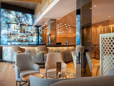 Moderner Hotelbarbereich mit beleuchteter Bar, bequemen Sesseln und elegantem Design.