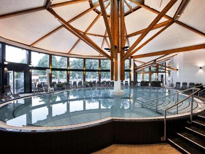 Vista interior de un jacuzzi con techo de vigas de madera y grandes ventanas