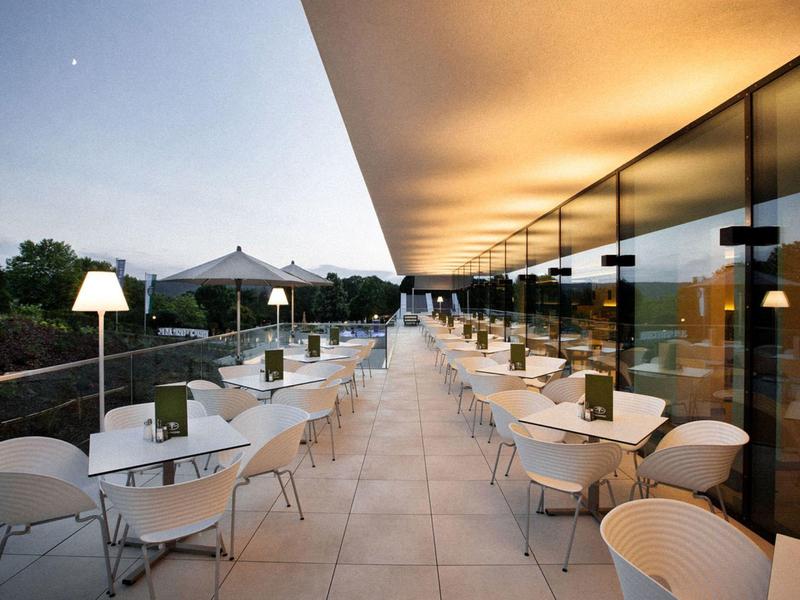 Terraza moderna de hotel con sillas y mesas blancas al anochecer