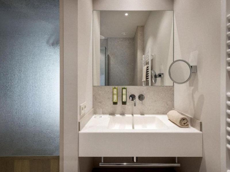 Baño moderno con lavabo doble, espejo y toallero en colores neutros.