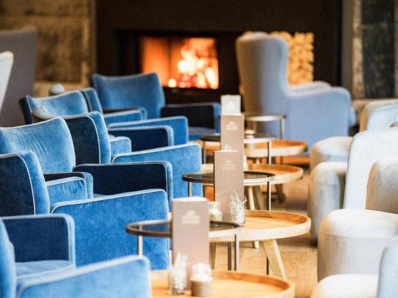 Zona lounge acogedora de hotel con sillones azules y blancos frente a una chimenea.